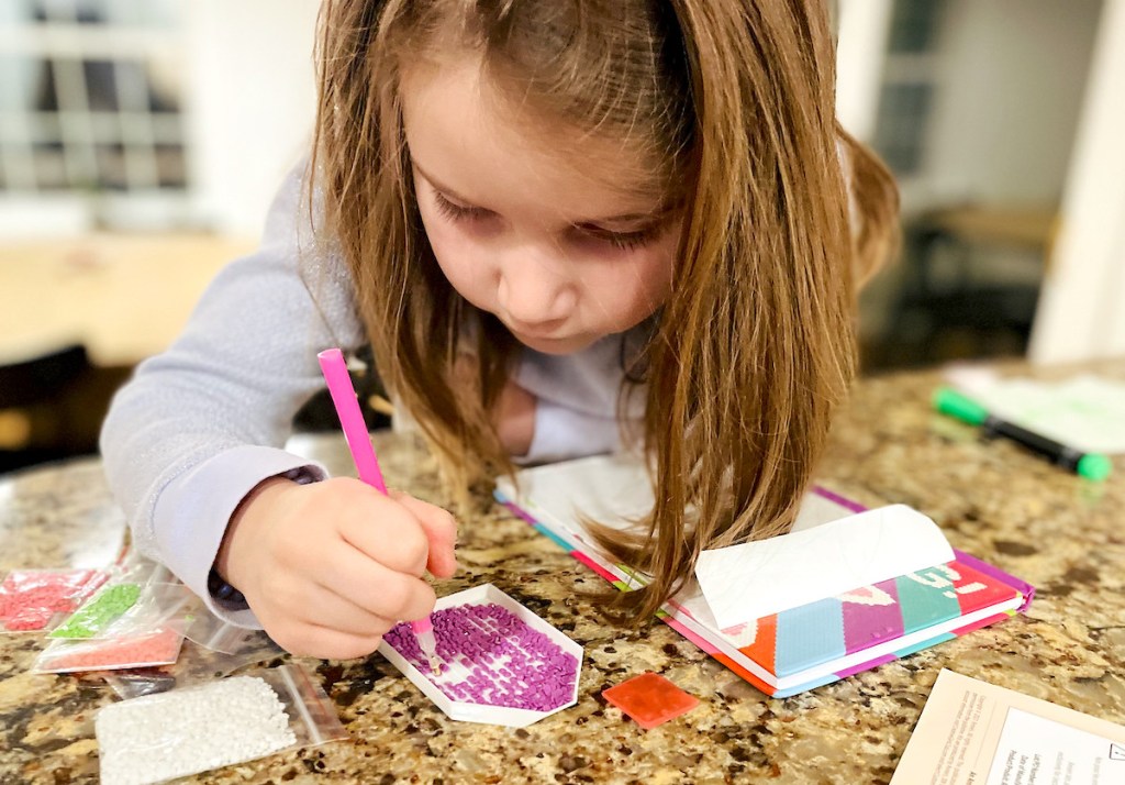 close up of girl picking up crafting beads on counter