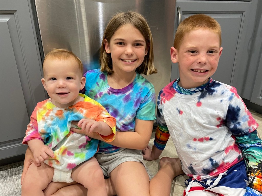 kids sitting on floor wearing tie dyed shirts