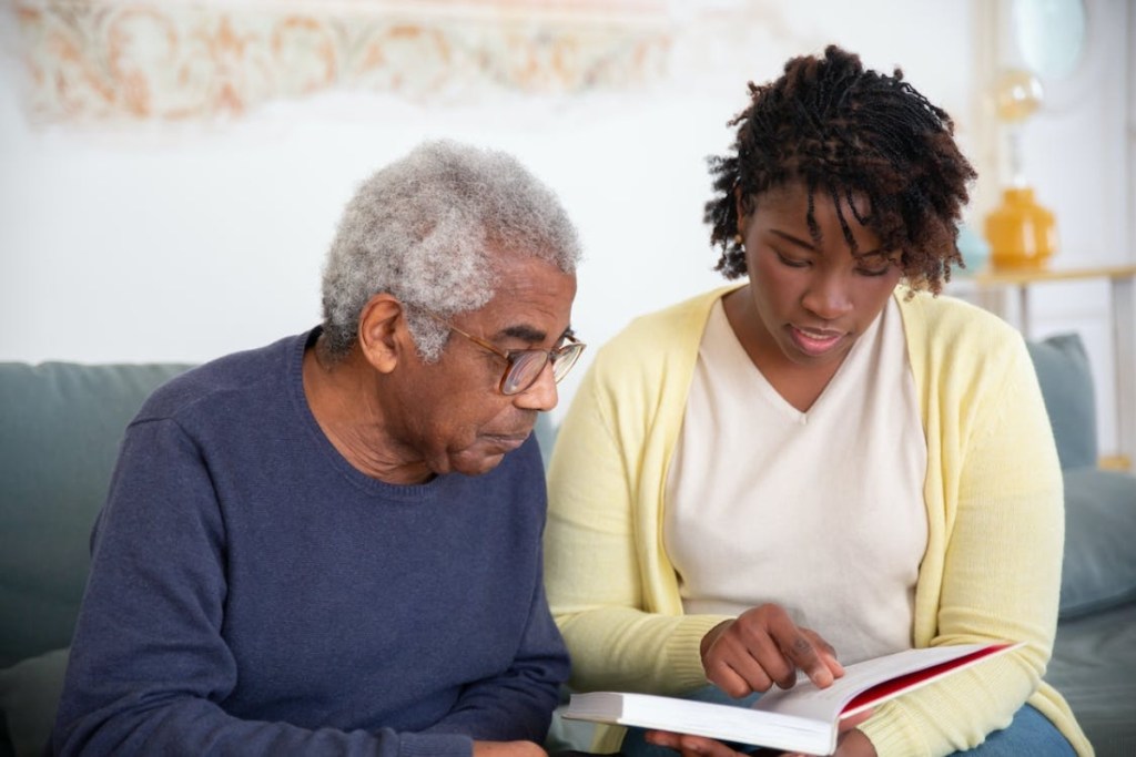 young woman reading a book to an older man