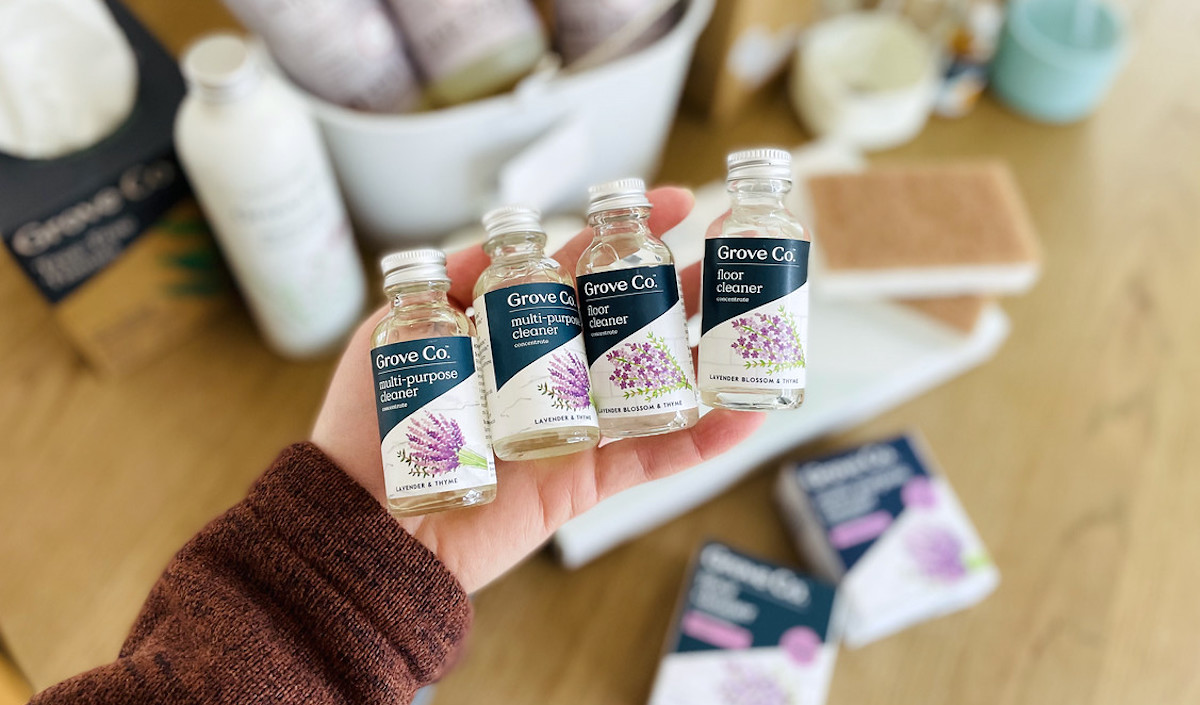 hand holding four small glass bottles of lavender cleaning concentrates