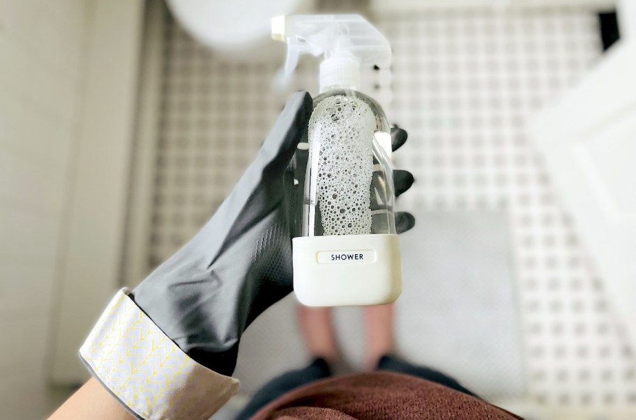 hand holding a clear white silicone bottle with shower label on it