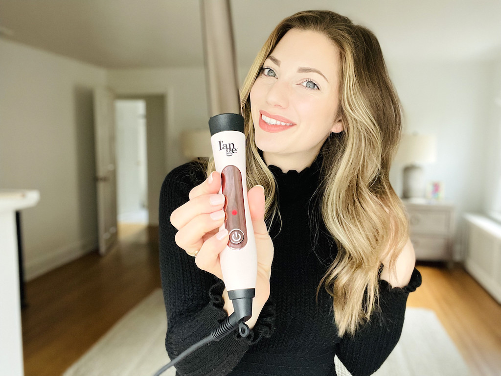 woman with beach waves holding lange hair curling wand