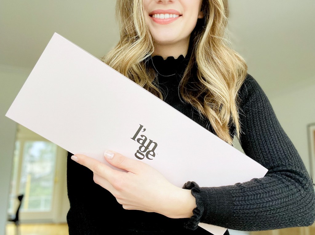 woman holding pink product box in arm smiling