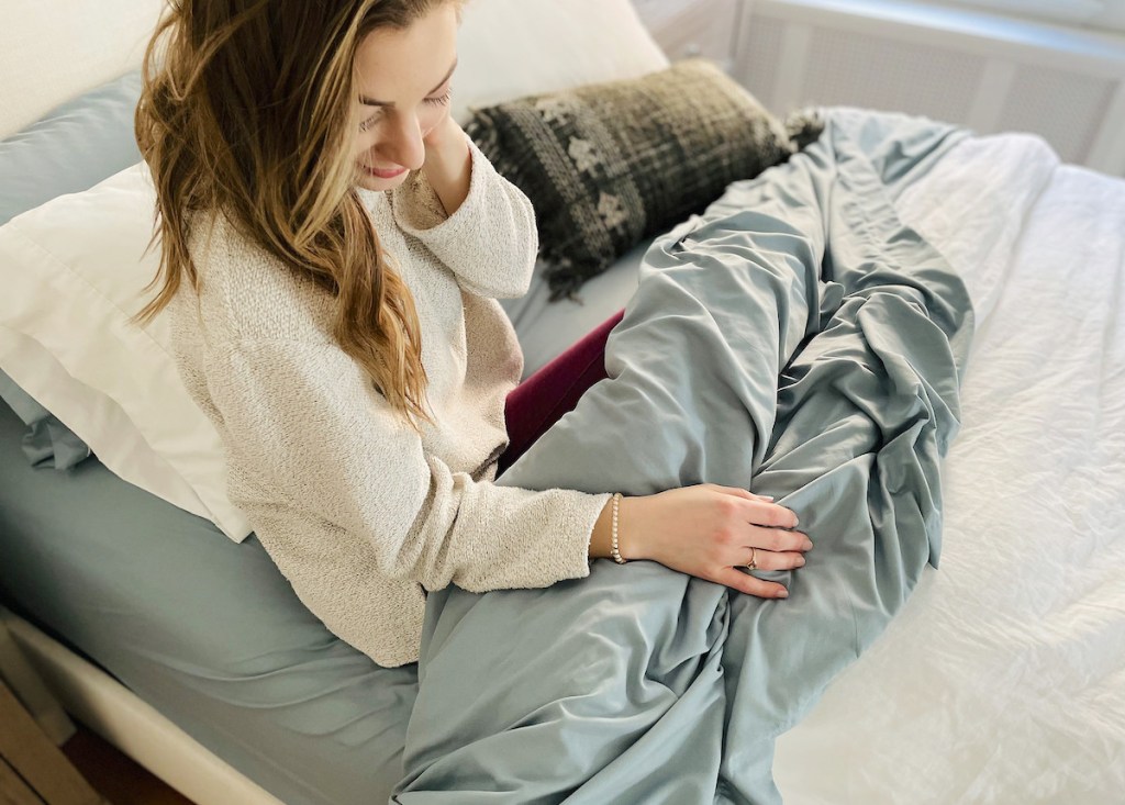 woman sitting on bed with blue walmart sweet home sheets