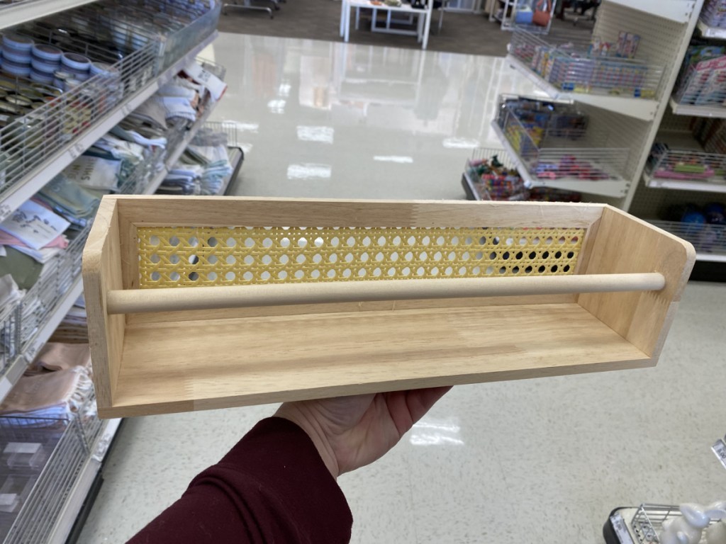 hand holding small wood bookshelf in store