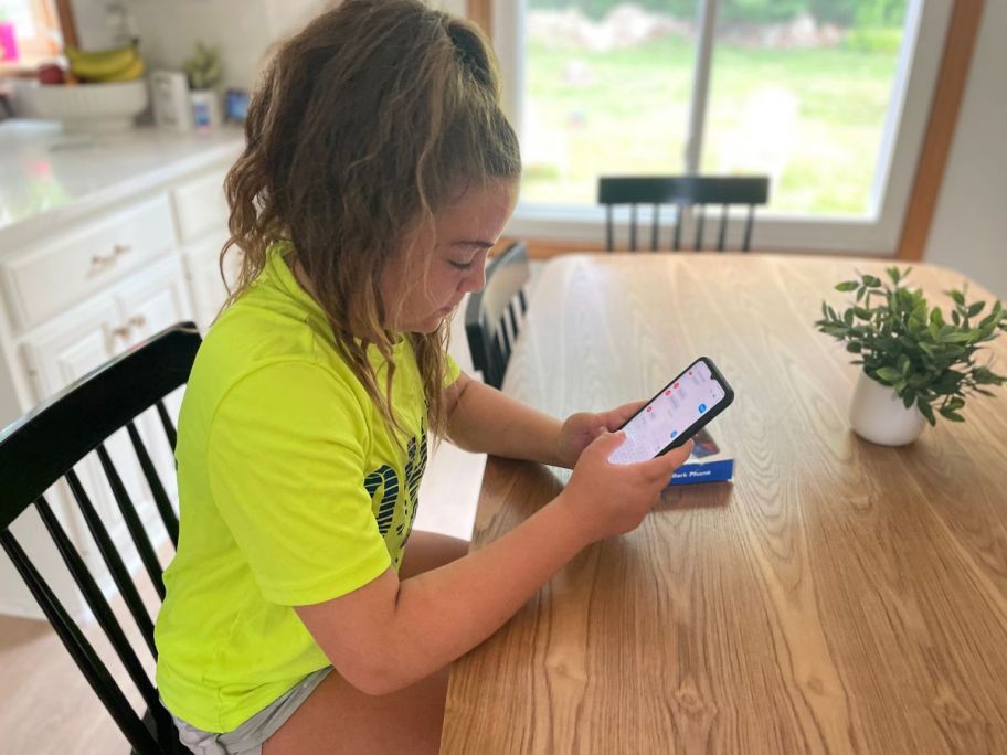 girl sitting at table looking at phone