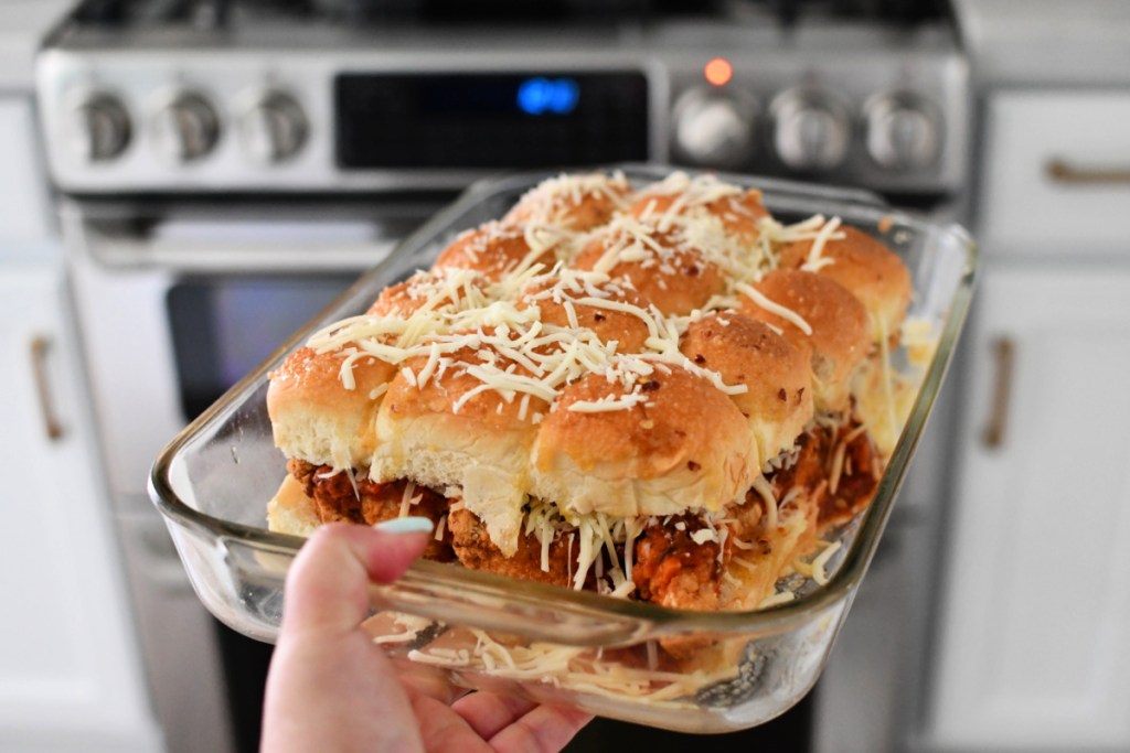 holding up a pan of parmesan sliders before going into the oven