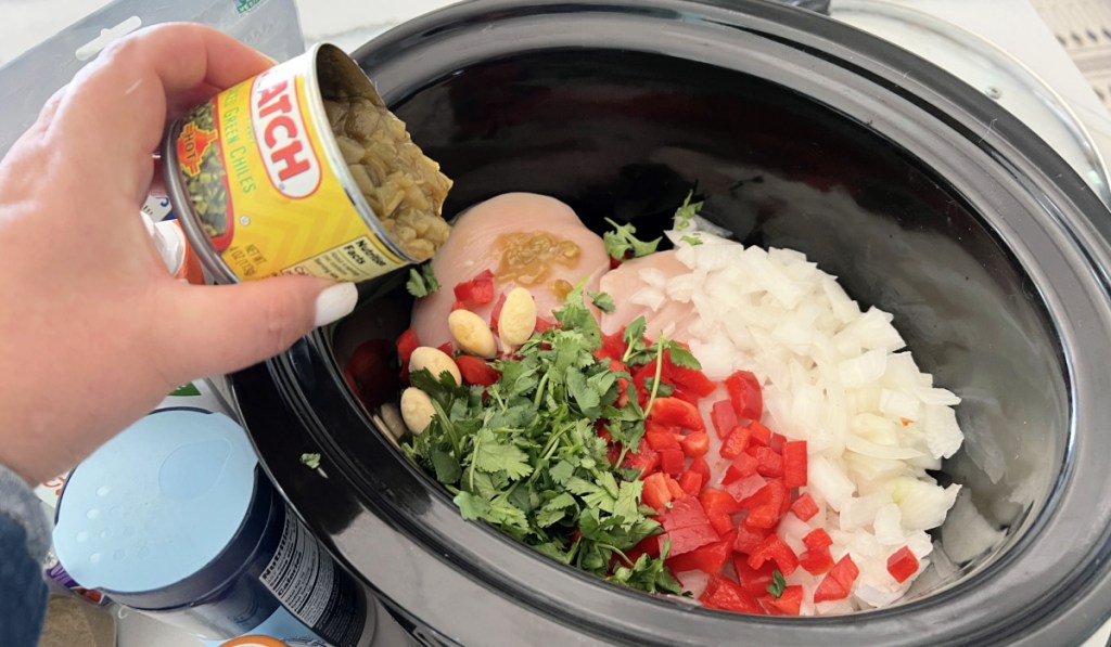 pouring green chilies into slow cooker soup