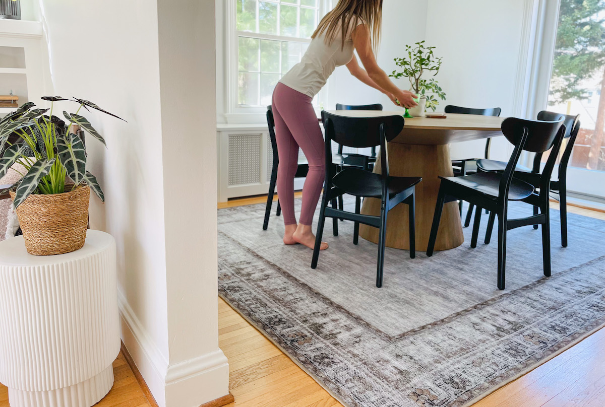 woman standing over dining room table with black chairs