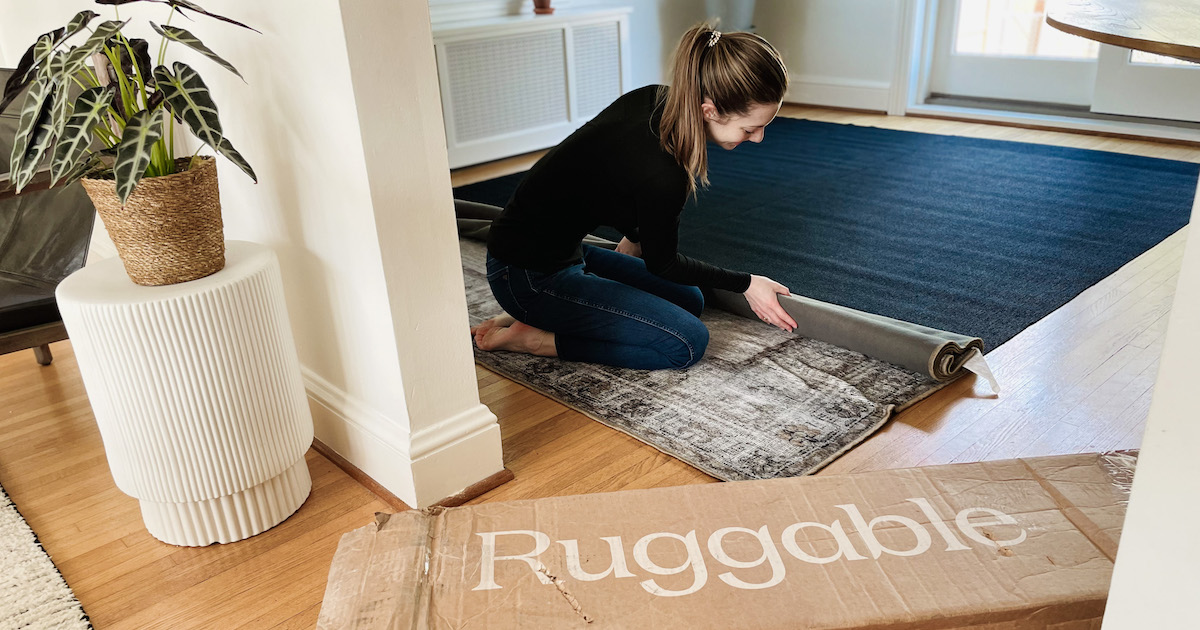 woman rolling out vintage rug on floor with ruggable box