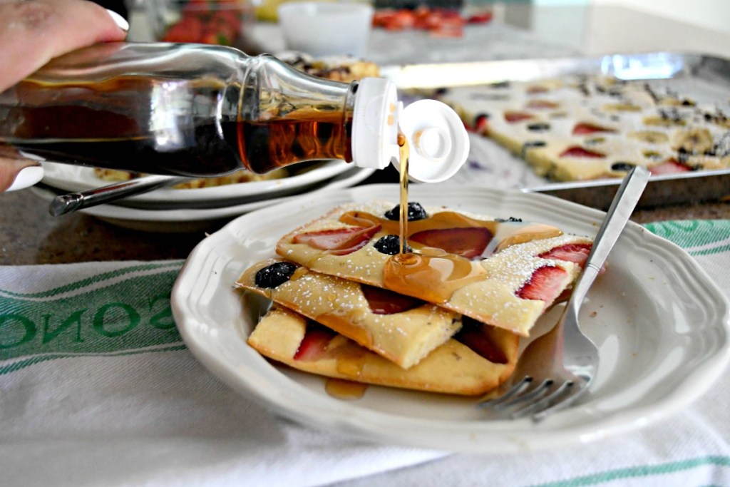 pouring syrup over strawberry and blueberry sheet pan pancake recipe