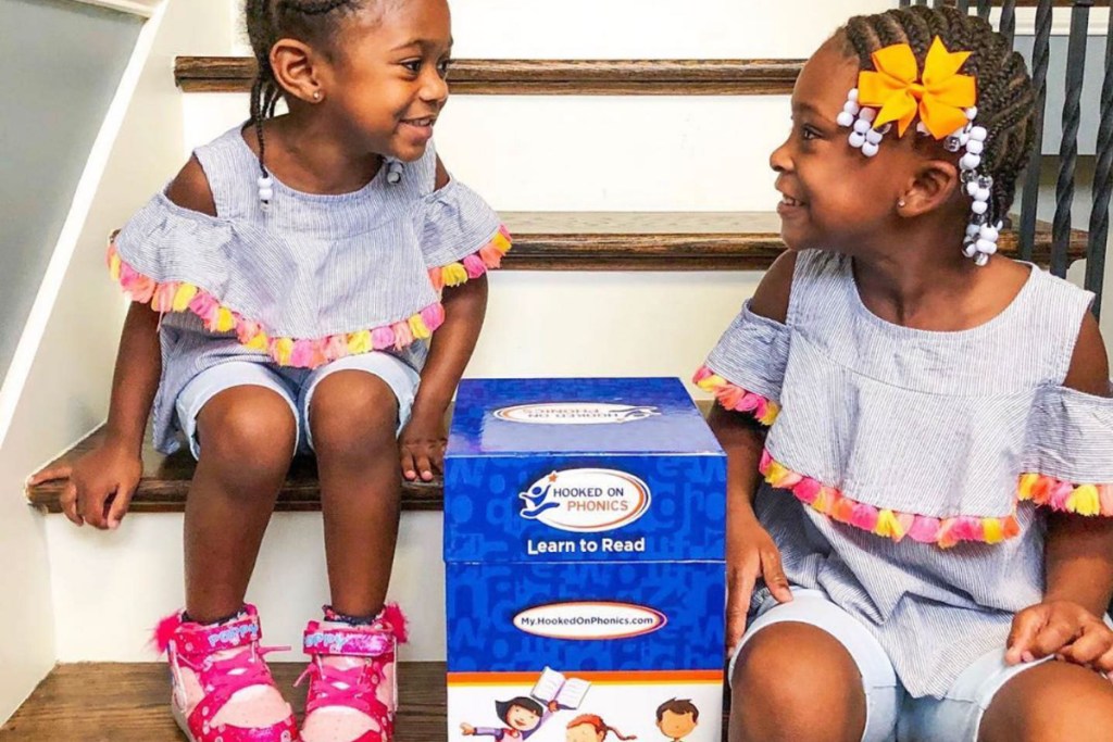 Girls sitting by Hooked on Phonics box