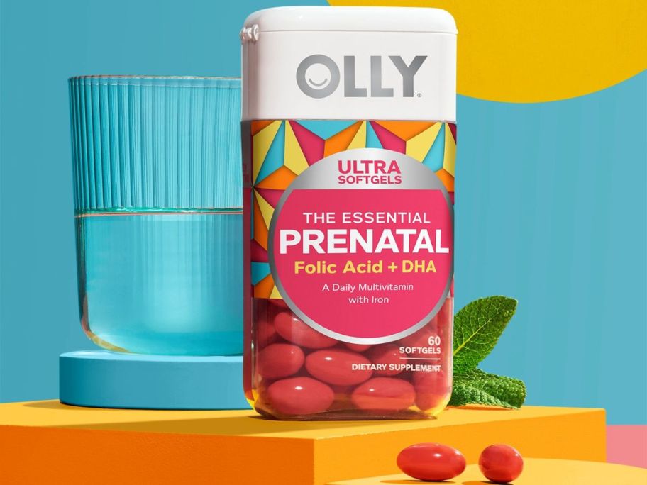 Bottle of Olly prenatal vitamins by a glass of water