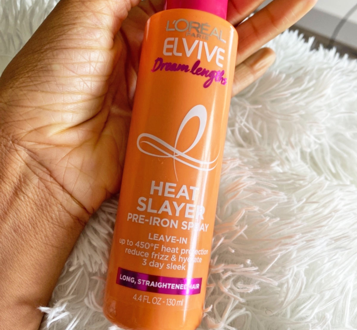 hand holding orange bottle of 'Oreal Paris Elvive Dream Lengths Heat Slayer Spray