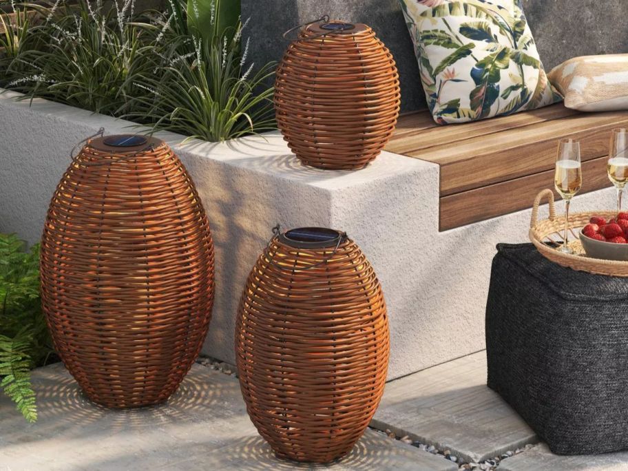 A patio with three different size Threshold Resin Wicker Woven Solar LED Outdoor Lanterns 