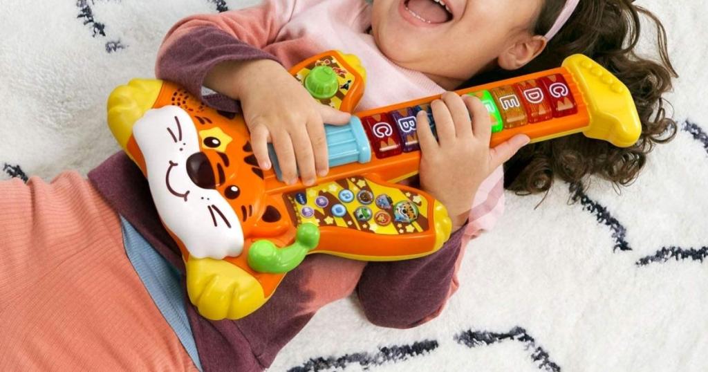 girl with Vtech Zoo Jamz Tiger Rock Guitar