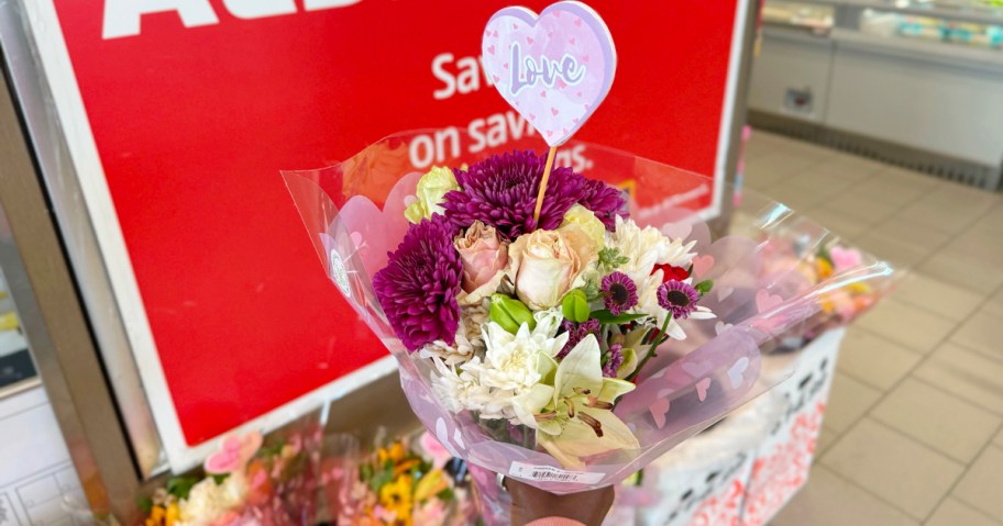 hand holding purple and white flower bouquet