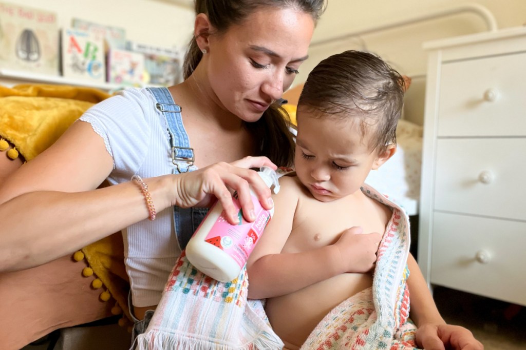 mom putting lotion on baby