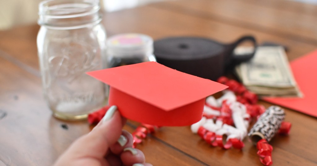 holding a paper graduation cap