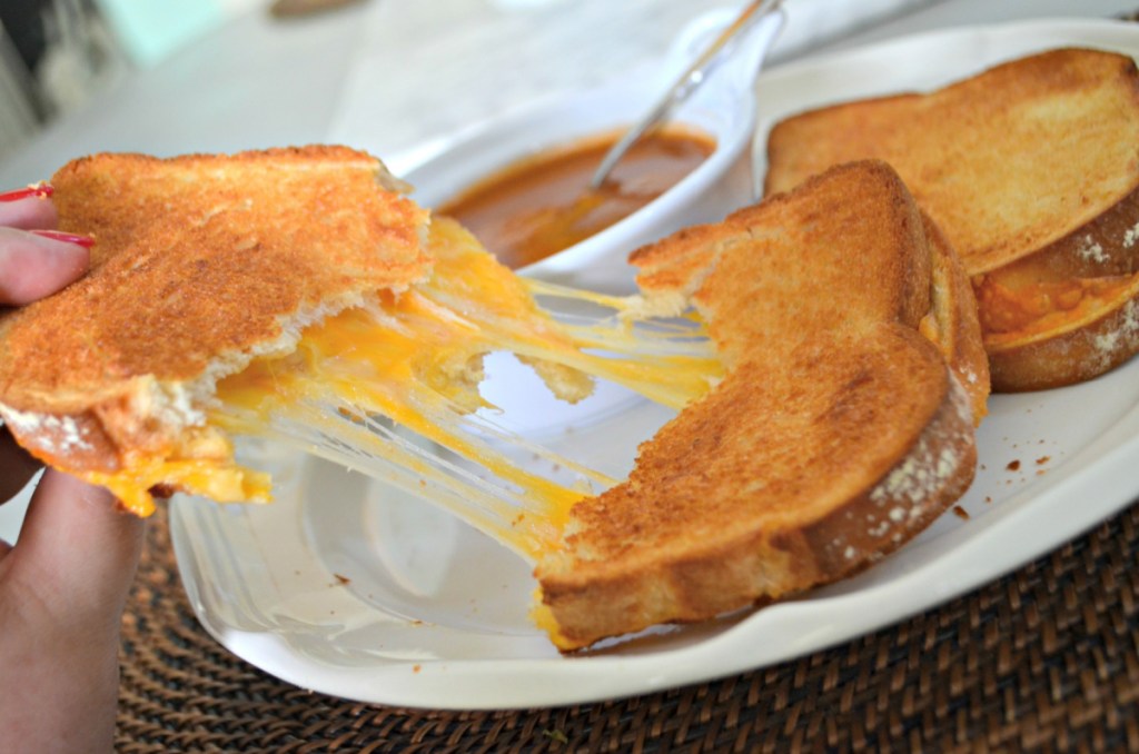 hand holding a gooey sandwich and showing how to make grilled cheese in the air fryer