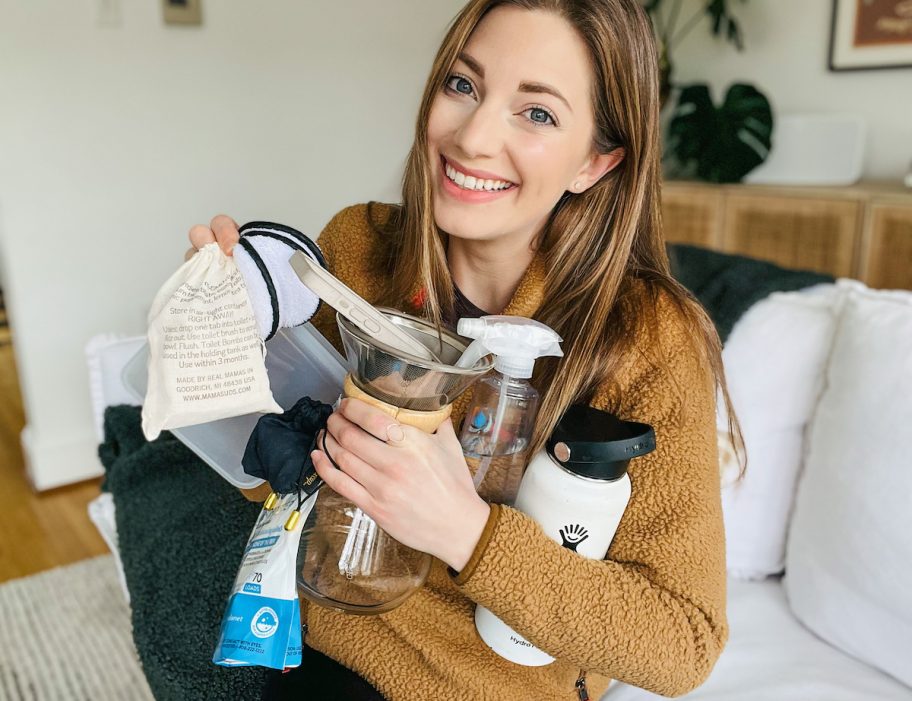 woman holding various reusable sustainable products on couch