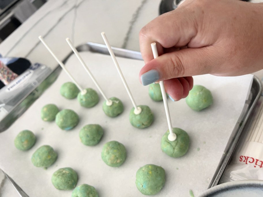 sticking cake pop sticks into cake pops