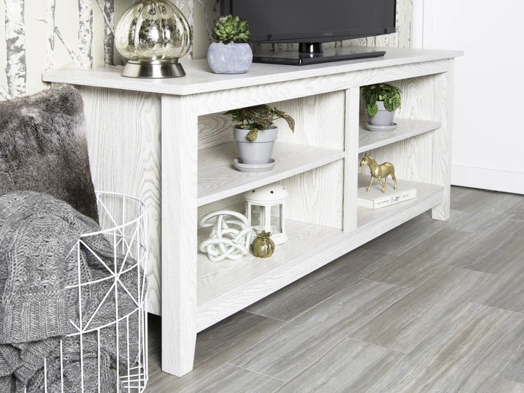 white tv stand next to basket with gray blankets