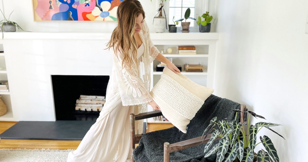 woman holding pillow over chair in living room