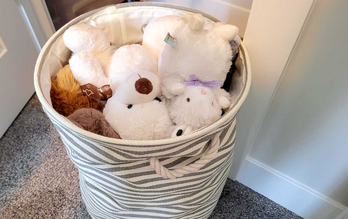 canvas bin with stuffed animals piled inside