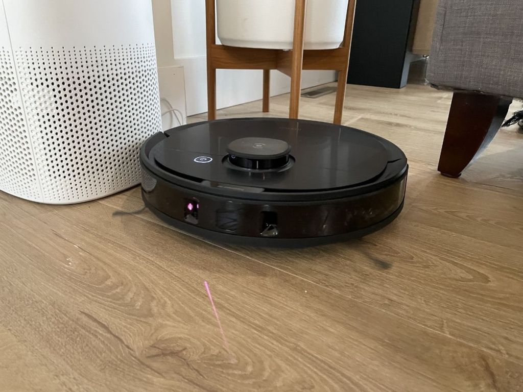 robot vacuum cleaner on a hardwood floor near furniture