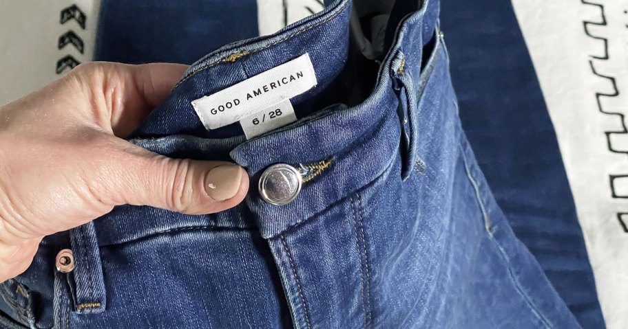 woman holding pair of good american jeans