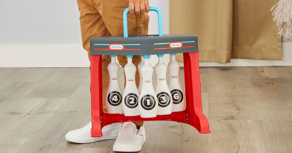 boy carrying bowling toy set