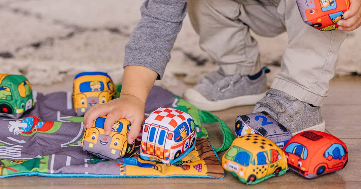 young boy playing with the melissa and doug take along town play mat