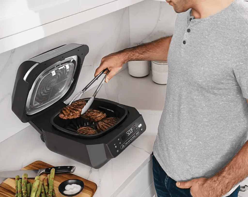 Man cooking using a Ninja Foodi Smart 5 in 1 air fryer from Sam's Club's May Savings Event