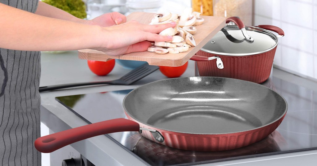 woman putting mushrooms into red fry pan