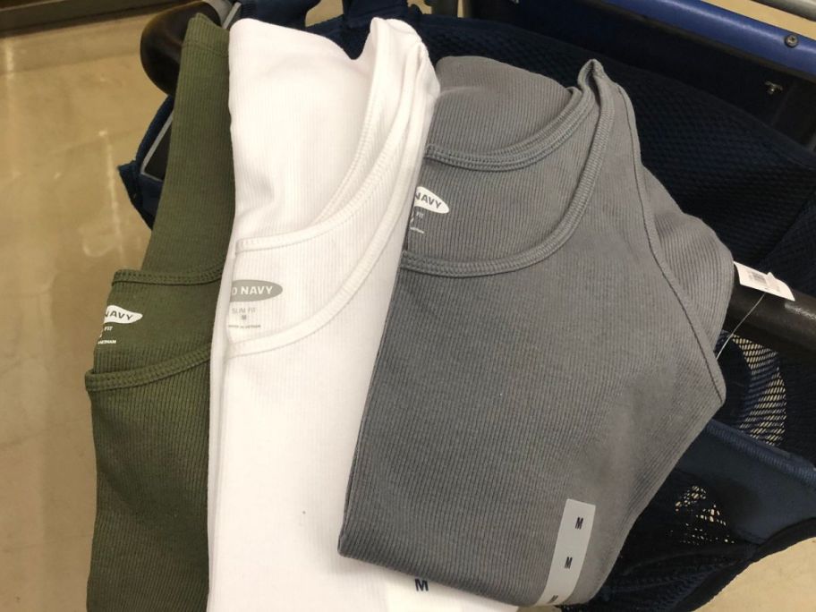 3 Old Navy Women's Tank Tops fanned out being held in a hand over a shopping cart