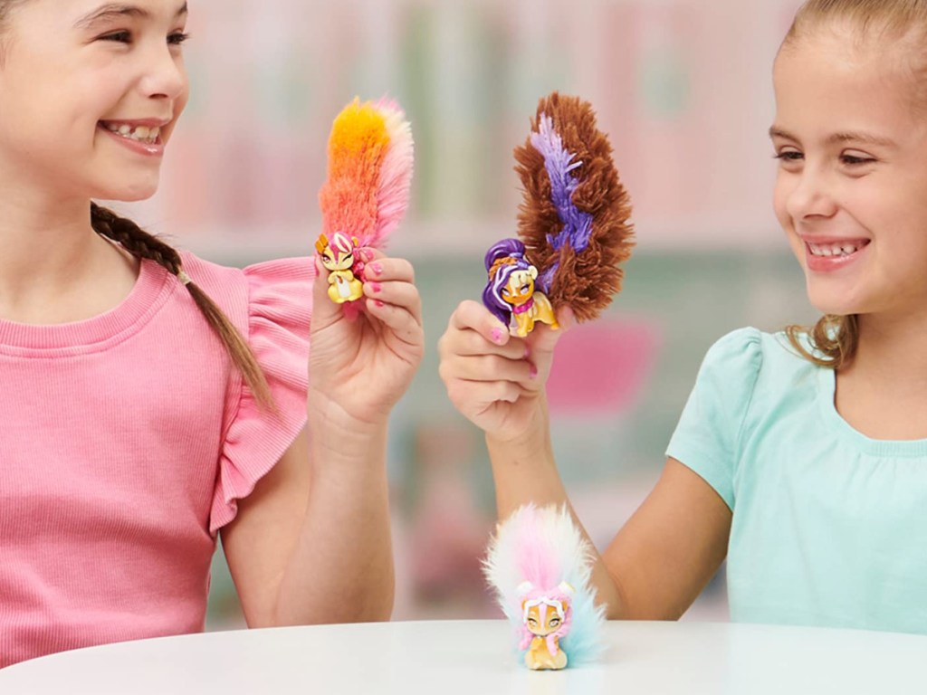 two girls sitting at table playing with three squirrel toys with long tails