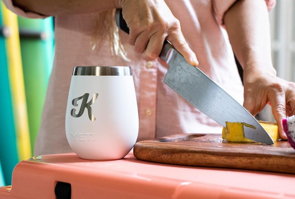 White YETI wine glass with a K on it and a woman cutting food behind it