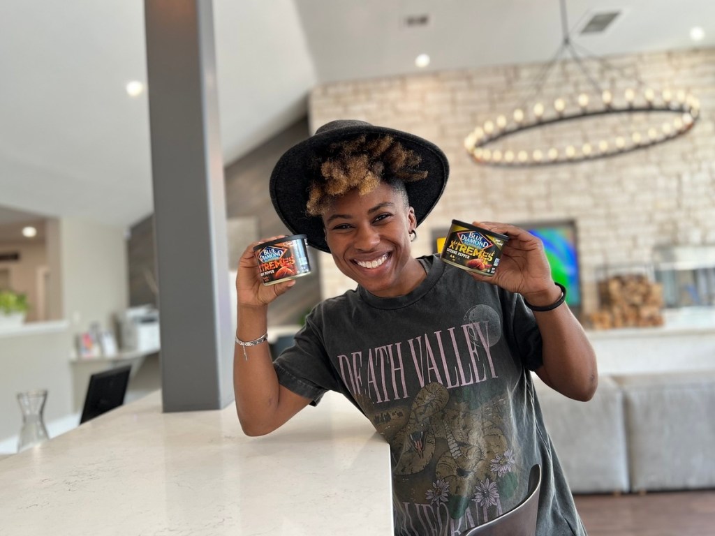 person holding 2 cans of almonds in kitchen