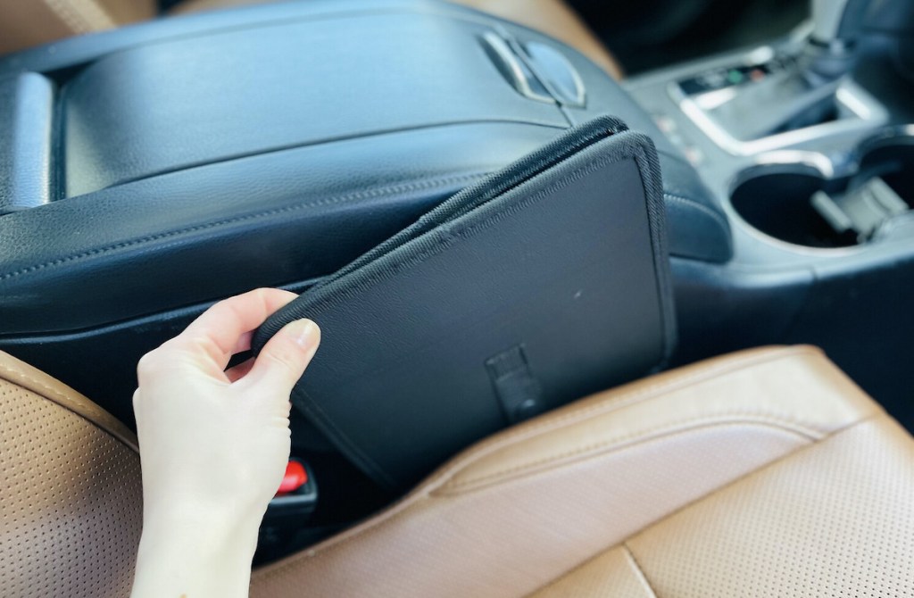 hand pulling out black collapsible trash can from the side of passenger seat