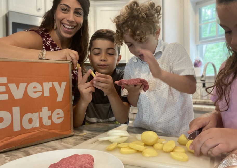 family posing around an EveryPlate box in their kitchen