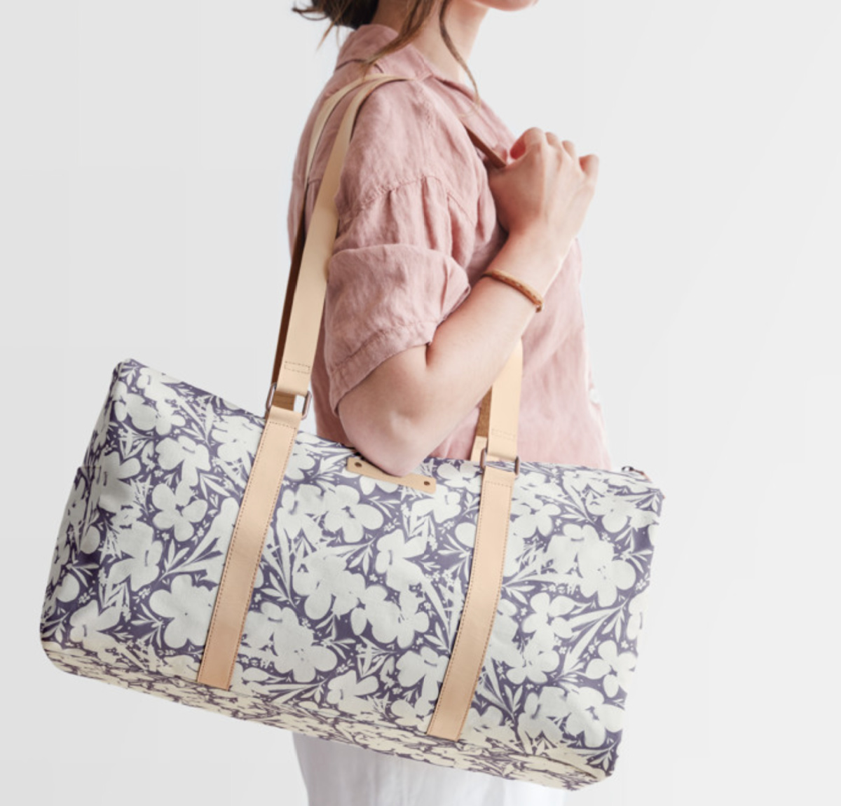 woman holding purple floral duffel bag