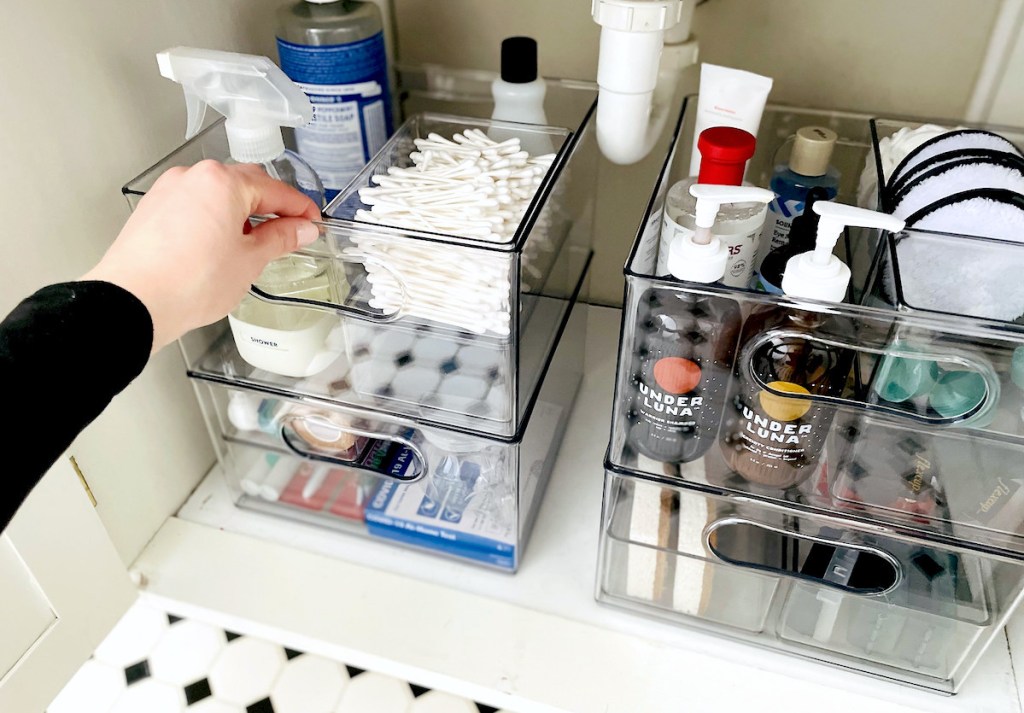 hand holding organized clear container under bathroom sink