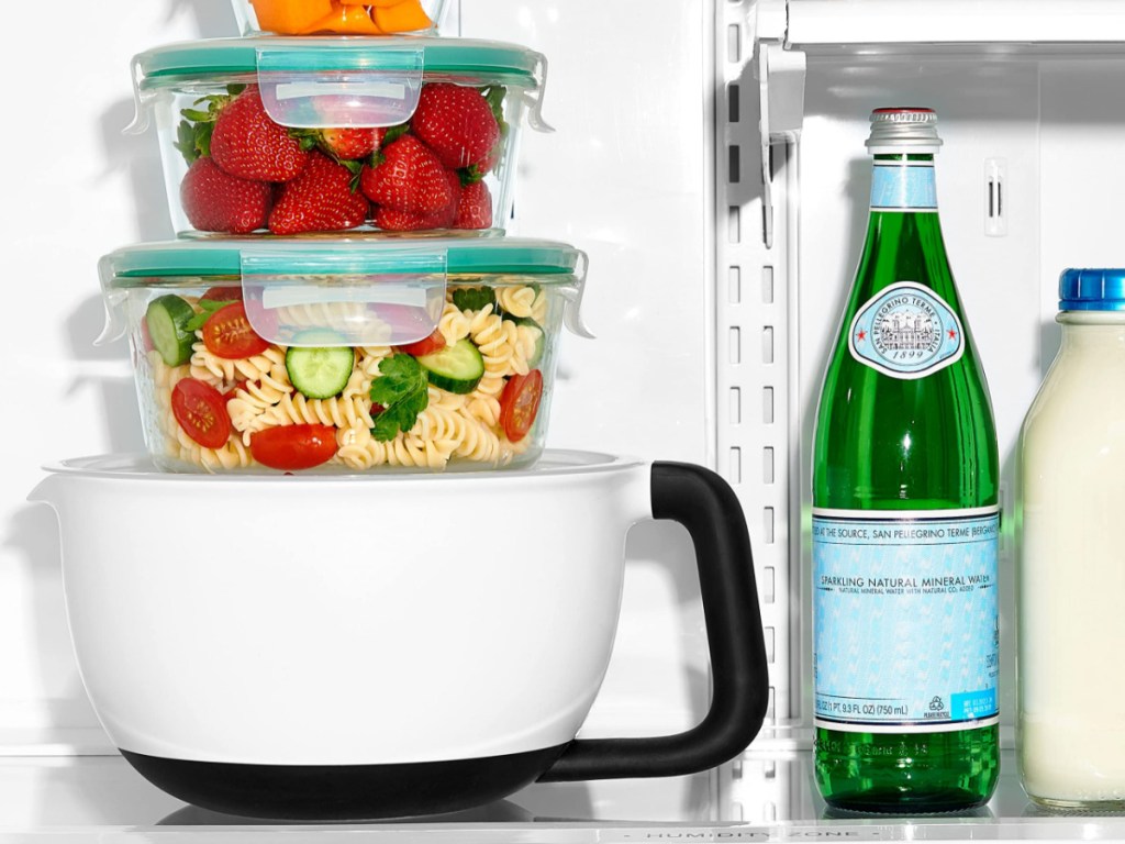 food storage containers stacked on top of black and white mixing bowl in fridge