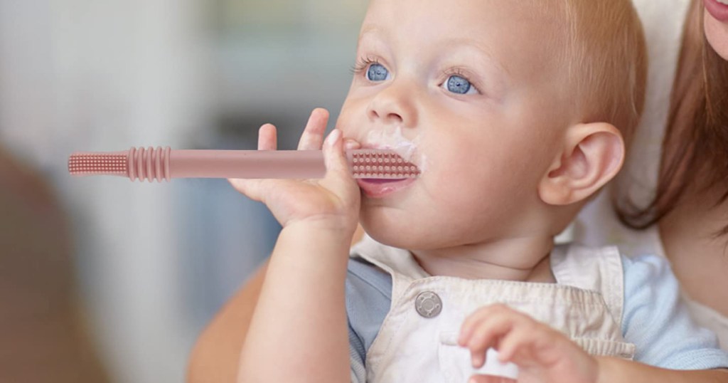 baby chewing on pink teething tube toy