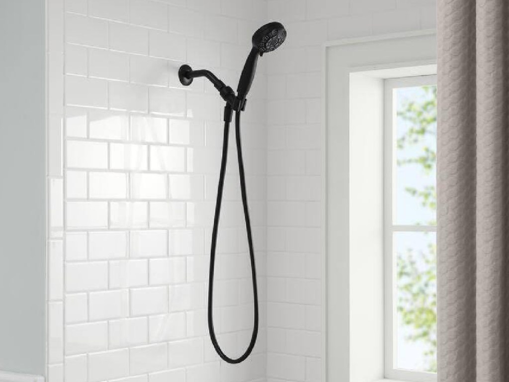 black shower head with handle displayed in the bathroom