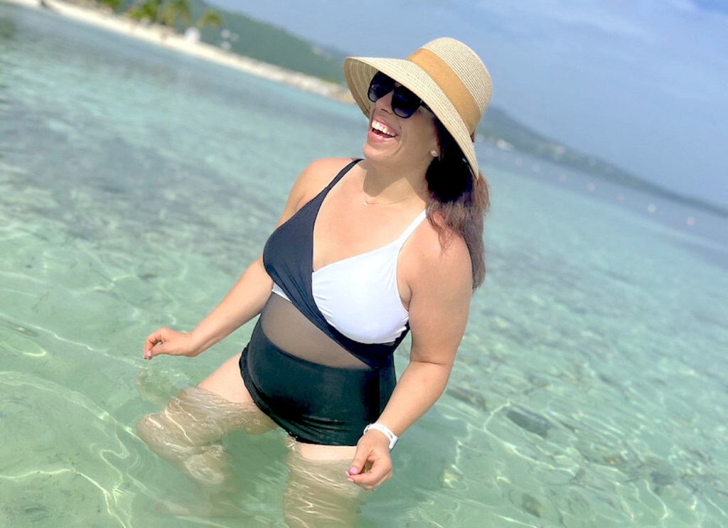 woman standing in clear ocean water wearing black and white modest swimwear