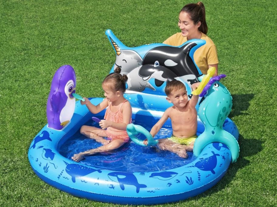 Kids and a mom playing in a Bestway H2OGO! Polar Pals Kids Inflatable Water Play Center