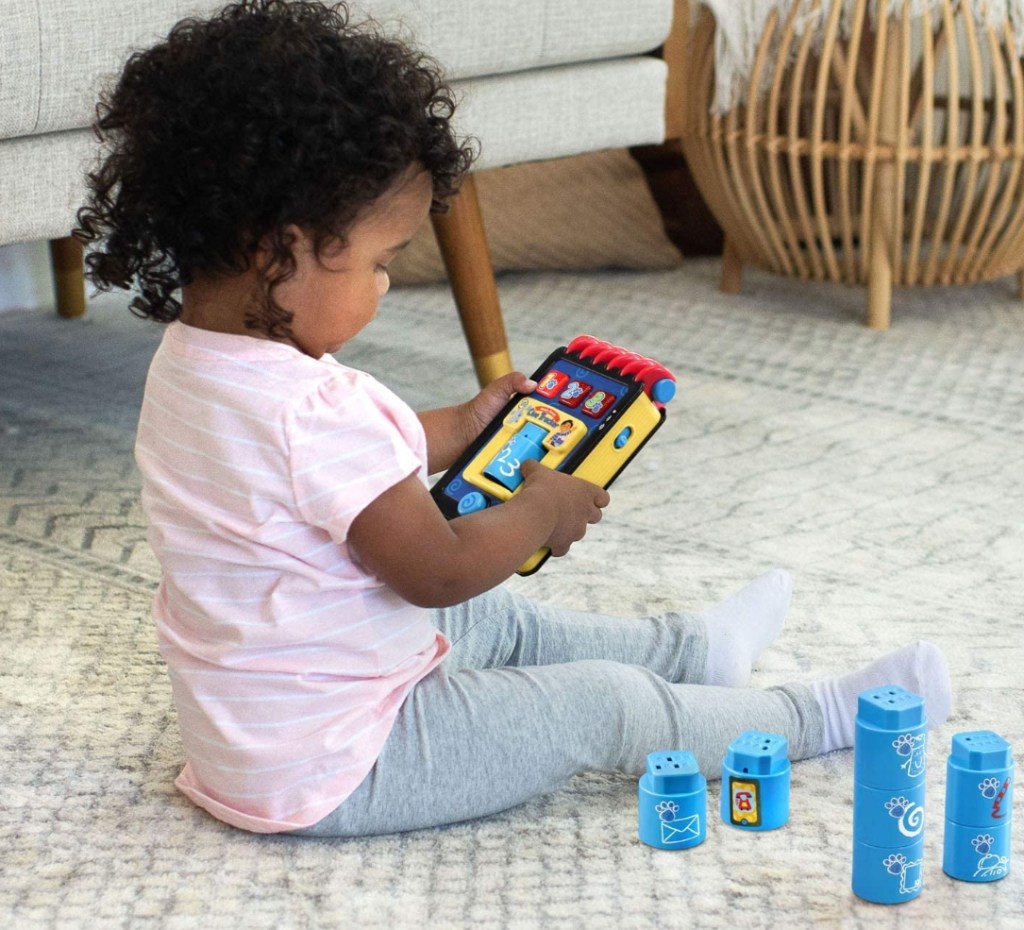 girl holding a Blue's Clues Handy Dandy Notebook