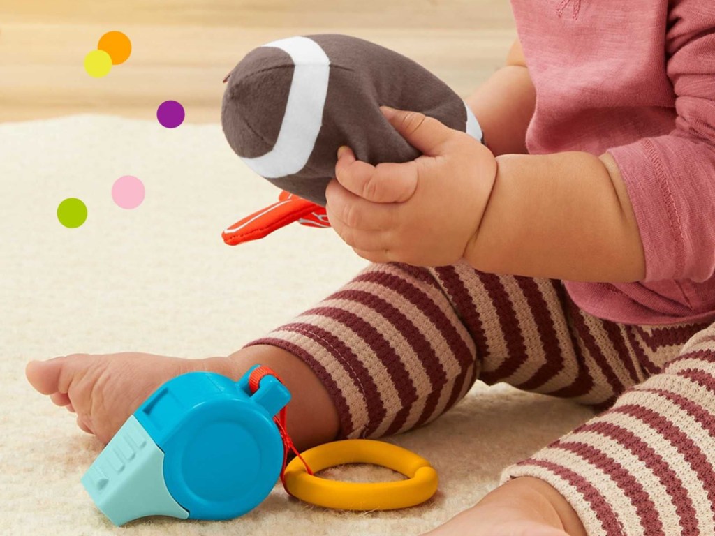 baby girl playing with three football themed toys